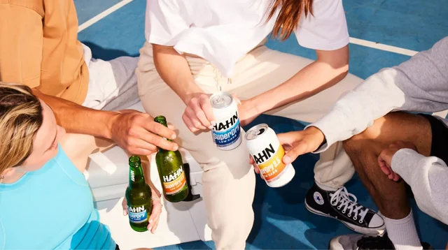 Friends enjoying a variety of Hahn beers on a blue sports court